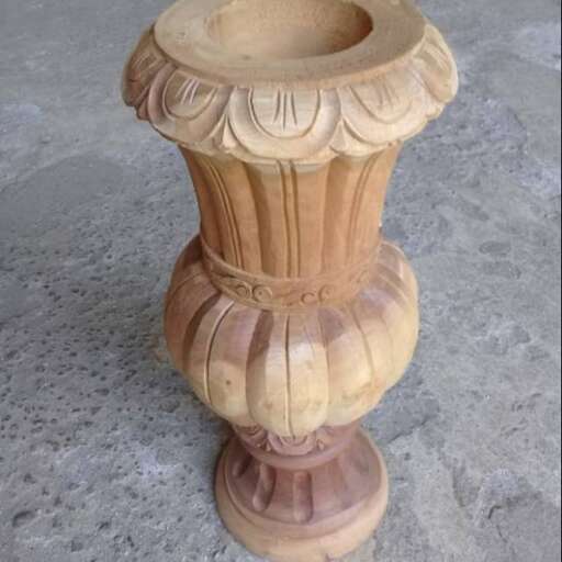 a wooden vase with a flower design on it.