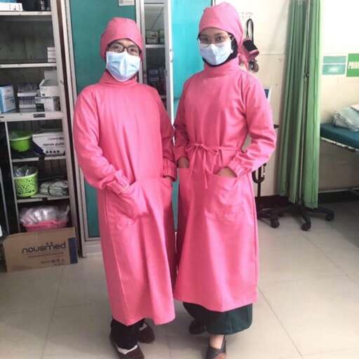 a couple of people wearing pink surgical clothes standing in a room.