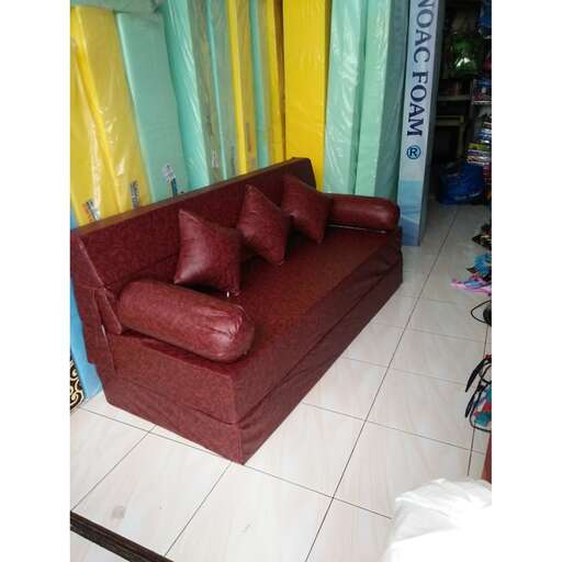 a red couch sitting on top of a white tile floor.