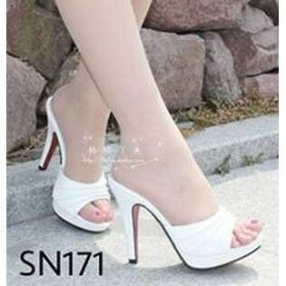 a woman in white high heels standing on a sidewalk.