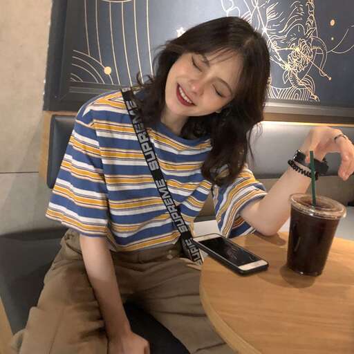 a woman sitting at a table with a drink and cell phone.