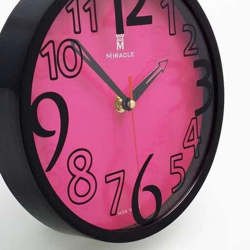 a pink clock with black numbers on it.