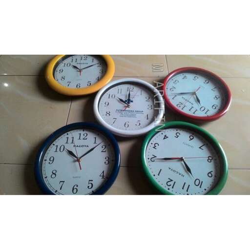 four different colored clocks on a tiled floor.
