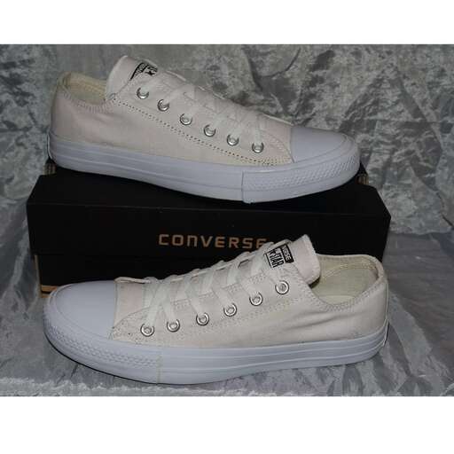 a pair of white sneakers sitting on top of a black box.