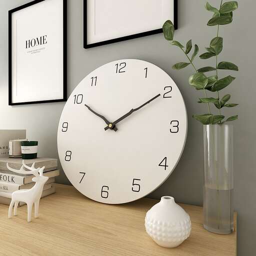 a clock on a table with a plant in a vase.