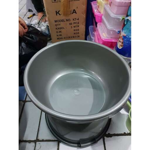 a large metal bowl filled with water on top of a tiled floor.