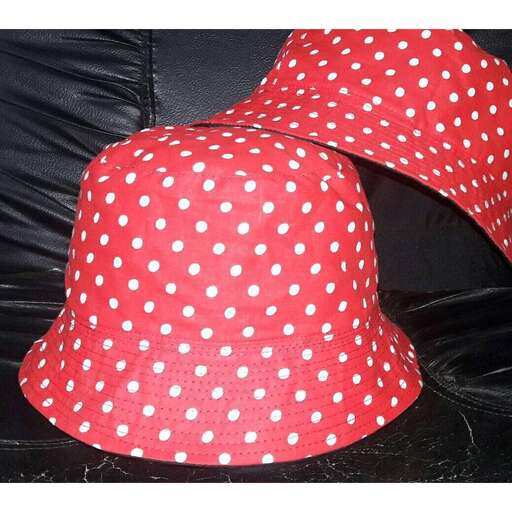 a red hat with white polka dots on a black couch.