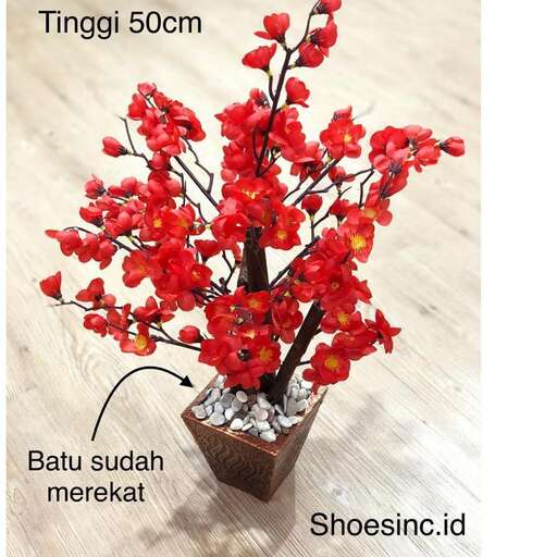 a small plant with red flowers in a wooden vase.