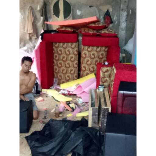 a man sitting on a chair next to a pile of furniture.