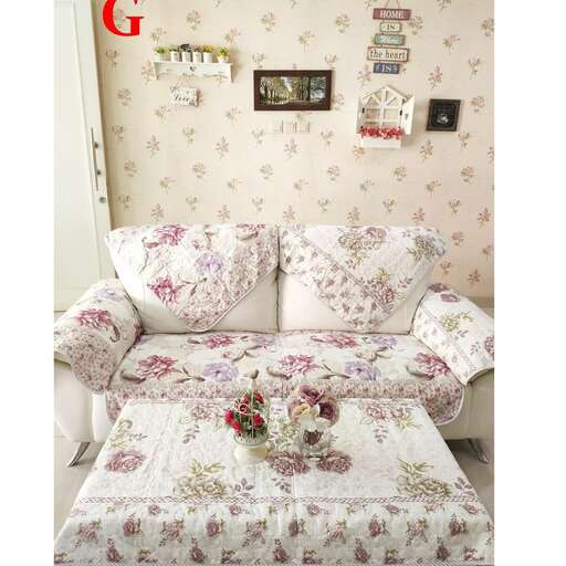 a couch with a flowered pillow and a flower vase on it.