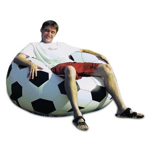 a man sitting on a soccer ball with his legs crossed.