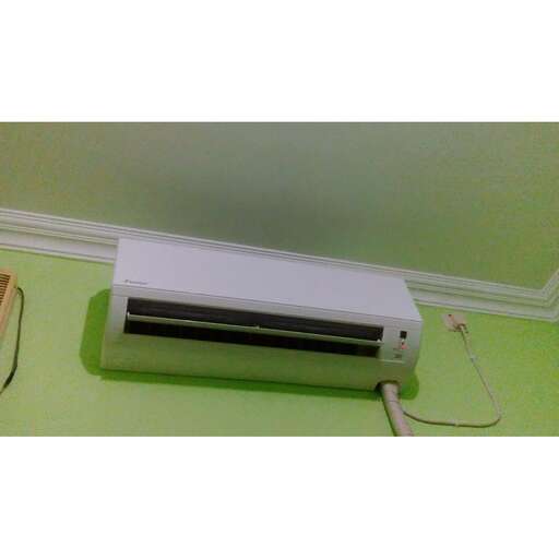 a small air conditioner sitting on a green wall.