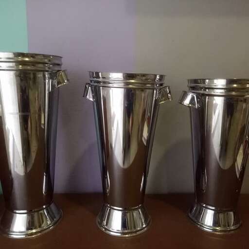 three silver containers are lined up on a table.