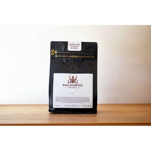 a black bag of coffee on a wooden shelf.