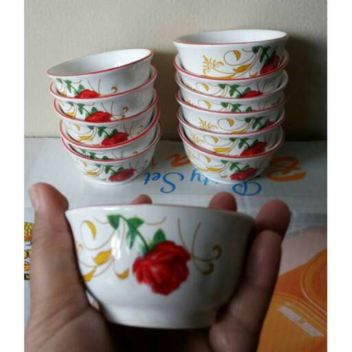 a hand holding a small bowl with a flower design on it.