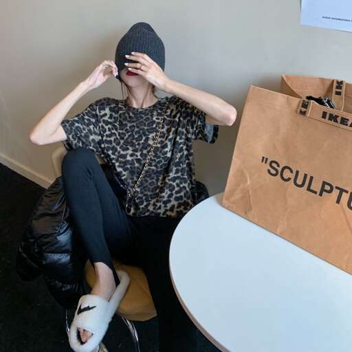 a woman sits on a chair next to a table with a bag on it.