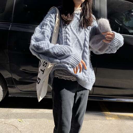 a woman in a sweater and jeans stands next to a black car.
