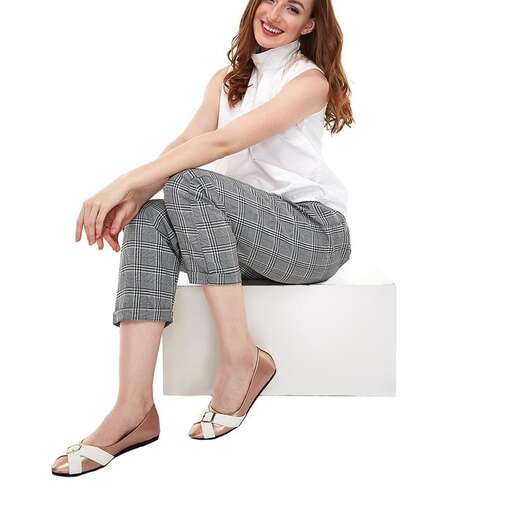 beautiful young woman sitting on a white bench in white background