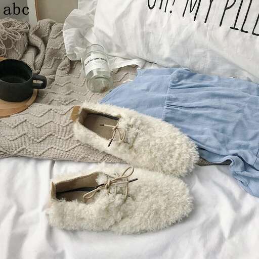 a pair of white boots sitting on a bed.
