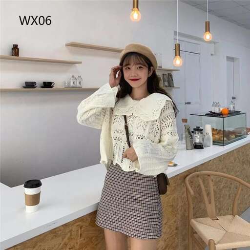 a woman in a sweater and a skirt standing in a room.