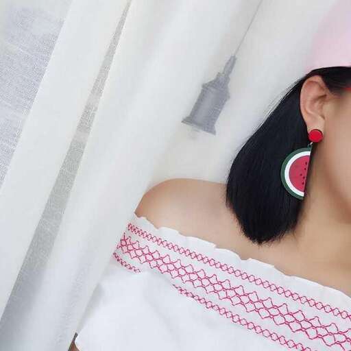 a woman wearing a white and red shirt and earrings.