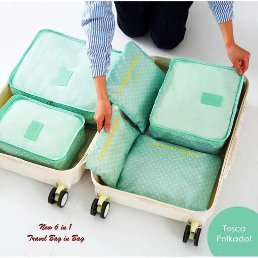 a person holding a suitcase with wheels and a pillow.