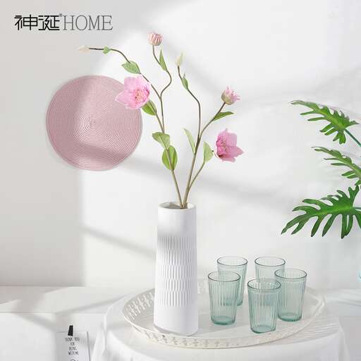 a white vase with pink flowers on a table.