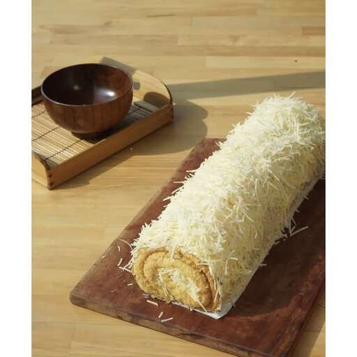 a rolled up roll of food on a wooden board.