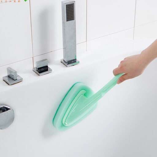 a person washing a sink with a green toothbrush.