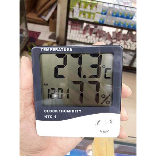 a person holding a digital clock in front of a store.