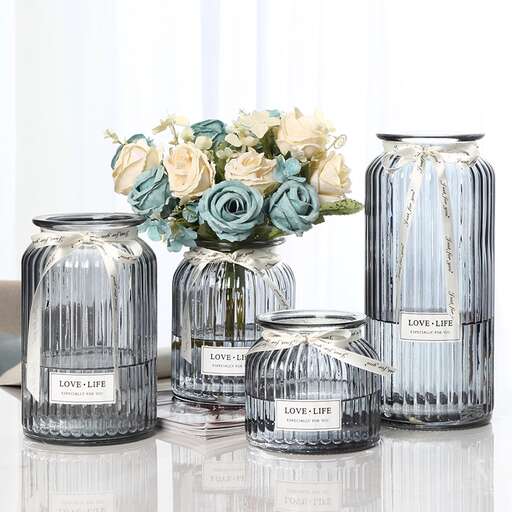 three glass jars with flowers in them on a table.