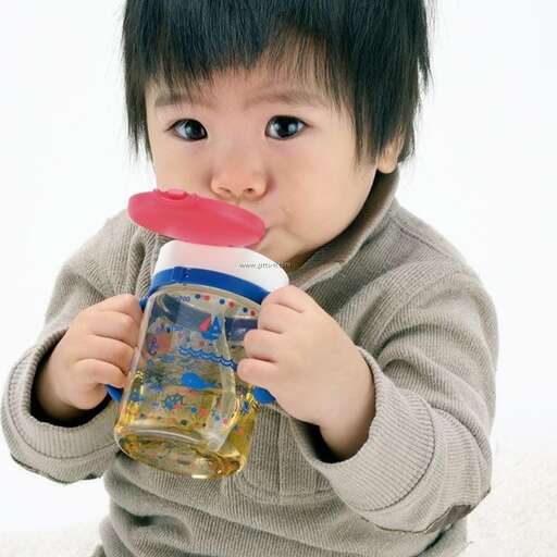 a baby boy drinking from a jar with a lid.