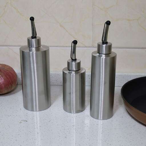 three metal canisters with toothbrushes in them on a counter.