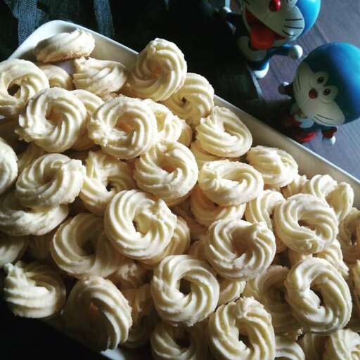 a plate of cupcakes with a stuffed animal in the background.