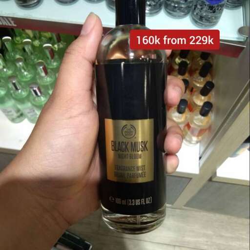a hand holding a bottle of black alcohol.