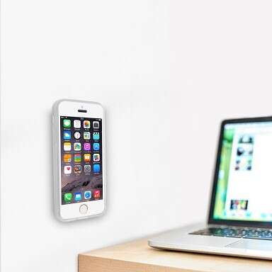 a smart phone mounted to a wall with a laptop on it.