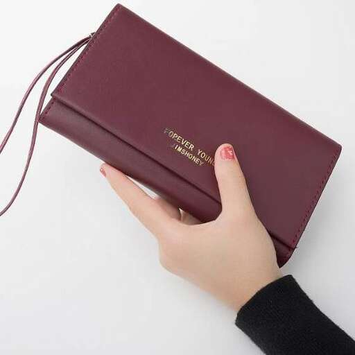 a woman holding a brown leather wallet.