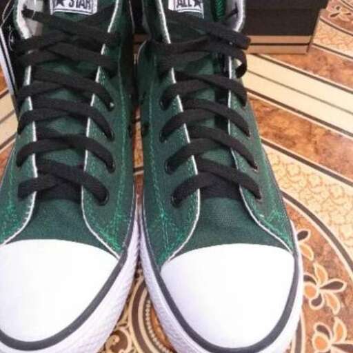 a pair of green and white sneakers with black laces.