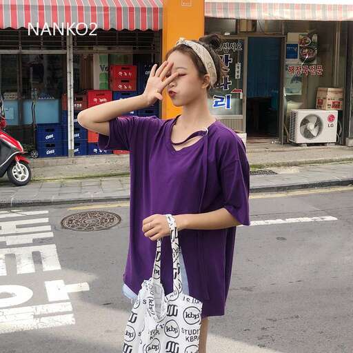 a woman in a purple shirt is holding a purse.