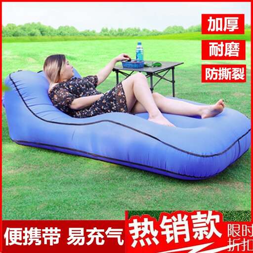 a woman laying on a bean bag chair in a park.