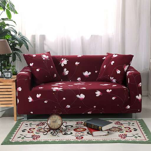 a red couch with a flowered seat and a plant in the corner.