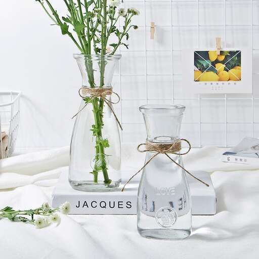 a table topped with a vase filled with water and flowers.