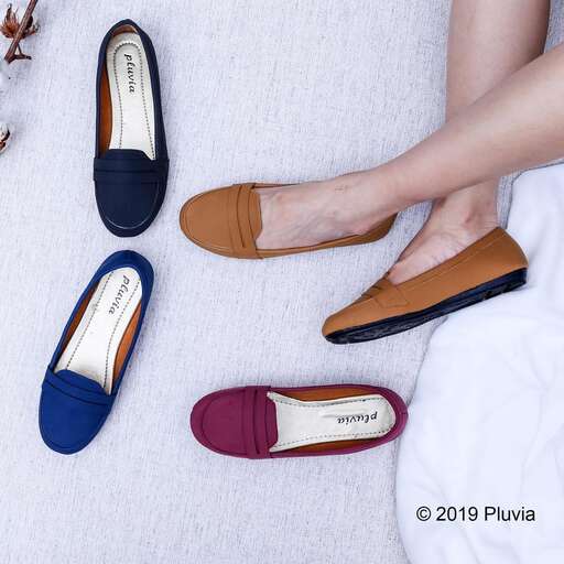 a woman's hand holding a pair of brown shoes.