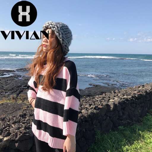 a woman in a pink and black striped shirt standing on a rock wall.