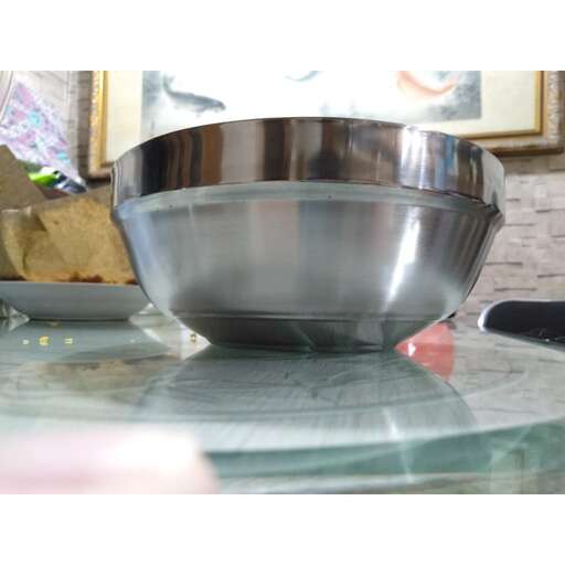 a silver bowl on a glass table with a knife.