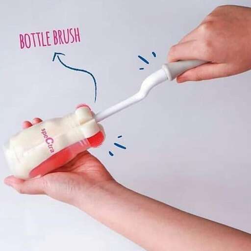 a person is holding a white brush over a white bottle.