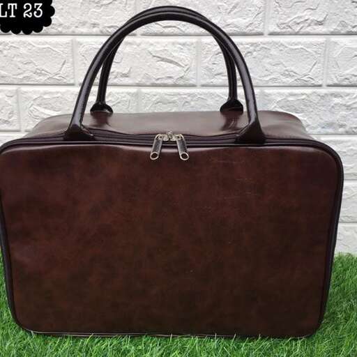 a brown leather briefcase with a handle on a green grass.