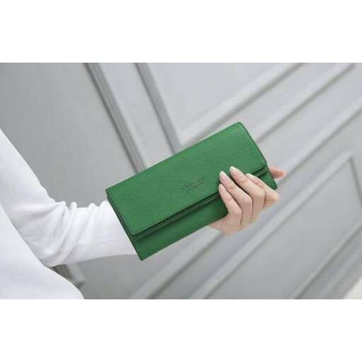a woman holding a green notebook in her hand.