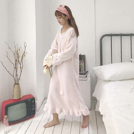a woman in a pink dress standing next to a bed.