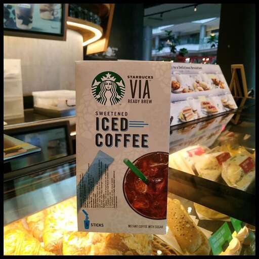 a sign in a display case with a coffee cup in it.